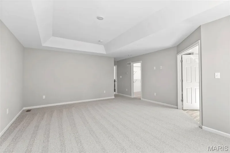 Empty room featuring baseboards, a raised ceiling, and light colored carpet — 2 Hermitage II at Harvest Estate, O'Fallon, MO 63368