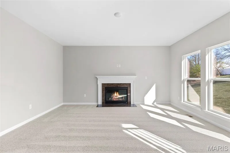 Unfurnished living room with carpet flooring, a premium fireplace, and baseboards — 2 Hermitage II at Harvest Estate, O'Fallon, MO 63368
