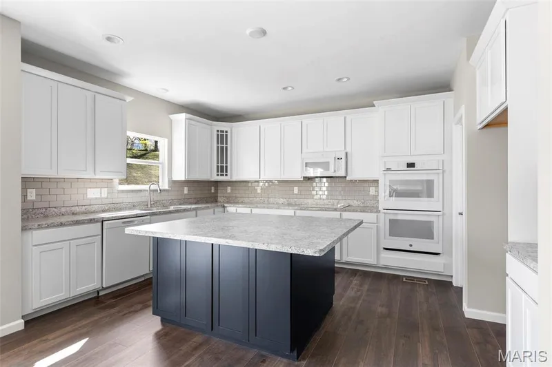 Kitchen with white appliances, dark wood finished floors, decorative backsplash, and recessed lighting — 2 Hermitage II at Harvest Estate, O'Fallon, MO 63368
