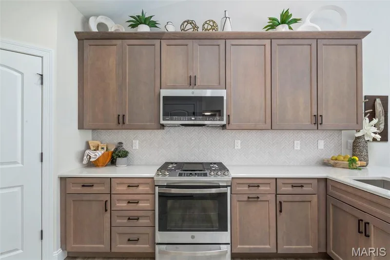 Kitchen with appliances with stainless steel finishes, tasteful backsplash, and light countertops — 2 Hickory at Harvest Estates, O'Fallon, MO 63368