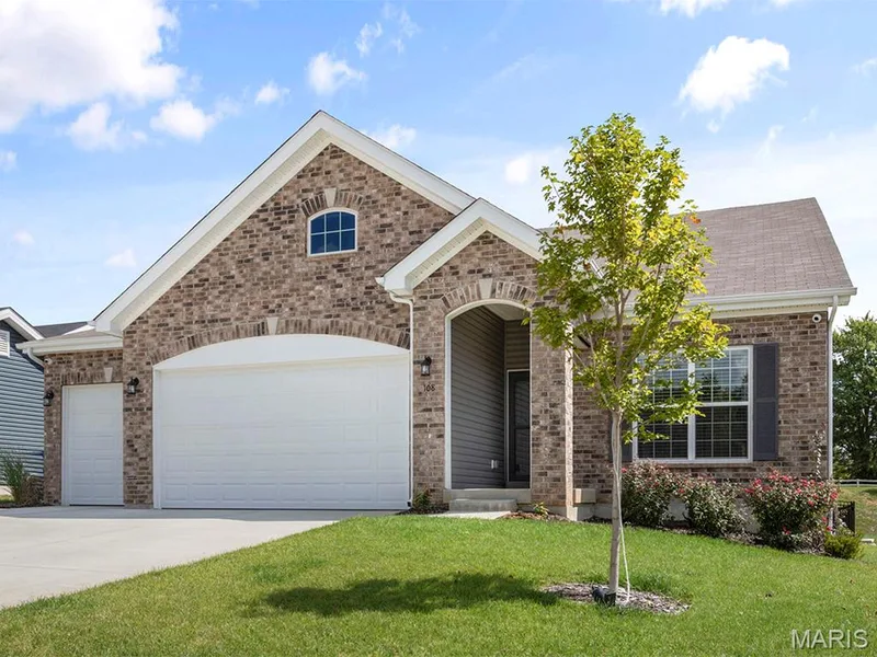View of front of property with a front yard, concrete driveway, a garage, and brick siding — 2 Maple Expanded at Harvest Est, O'Fallon, MO 63385
