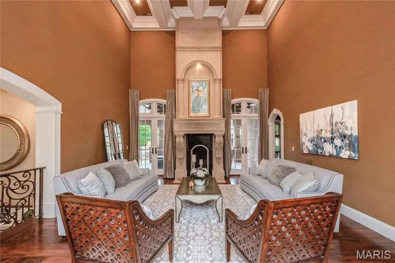 This view of the Great Room is taken from the Entry Foyer. The doorways on either side of the gas fireplace lead to the covered back porch, patio & swimming pool — 4 Slate River Way, Wentzville, MO 63385