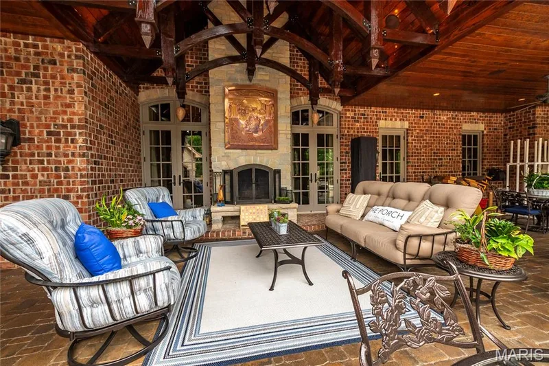 The next few photos are of the covered back porch. This sitting areas main feature is the  beautiful wood burning fireplace that welcomes you any time of year & the exposed decorative trusses that enhance the feel of this space — 4 Slate River Way, Wentzville, MO 63385