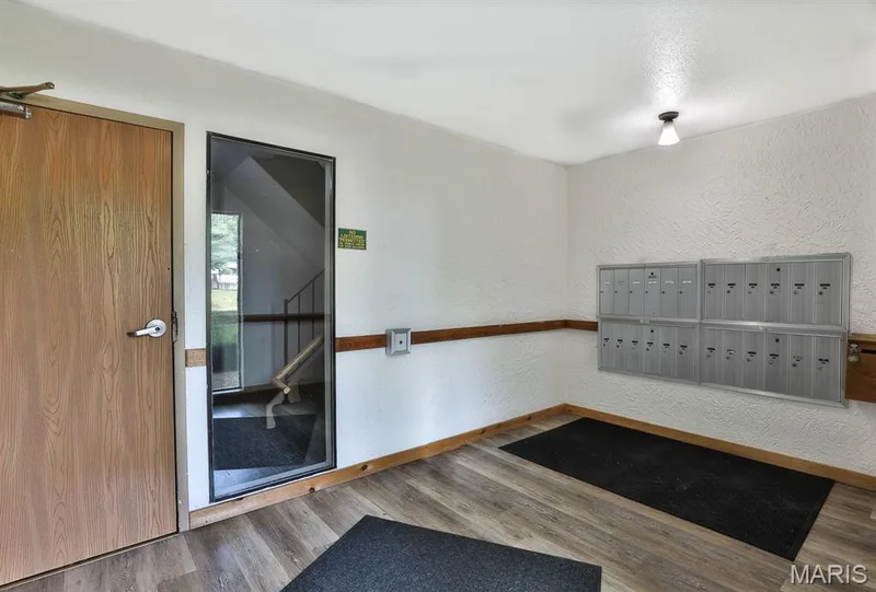 View of home's community with a textured wall and mail area — 1380 Heritage Landing #206, St Charles, MO 63303