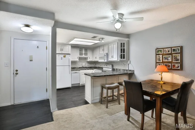 Kitchen with a peninsula, glass insert cabinets, backsplash, a ceiling fan, and a textured ceiling — 1380 Heritage Landing #206, St Charles, MO 63303
