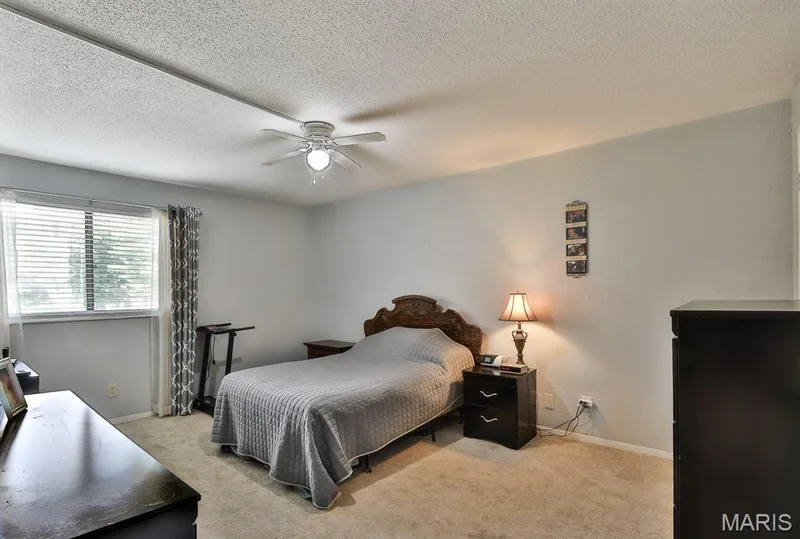 Bedroom featuring light colored carpet, a textured ceiling, and a ceiling fan — 1380 Heritage Landing #206, St Charles, MO 63303