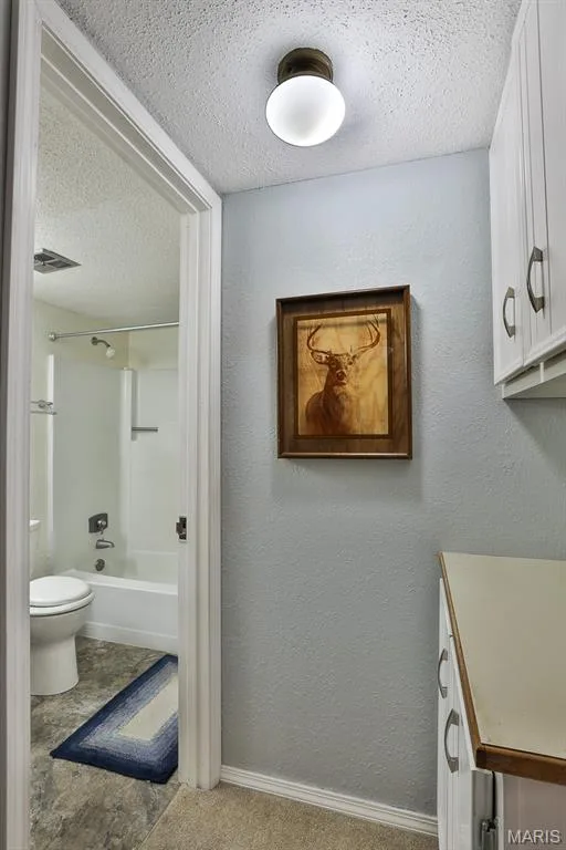 Bathroom with a textured ceiling, a textured wall, and shower / bath combination — 1380 Heritage Landing #206, St Charles, MO 63303