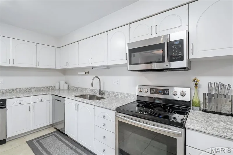 Kitchen with stainless steel appliances, white cabinets, and light tile patterned floors — 1511 Hampton Hall Drive #19 & 20, Chesterfield, MO 63017