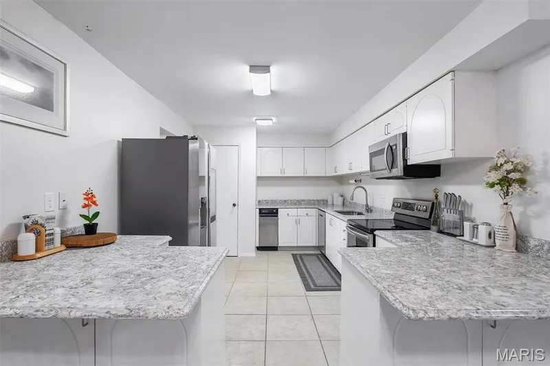 Kitchen with a peninsula, white cabinets, light countertops, appliances with stainless steel finishes, and light tile patterned floors — 1511 Hampton Hall Drive #19 & 20, Chesterfield, MO 63017