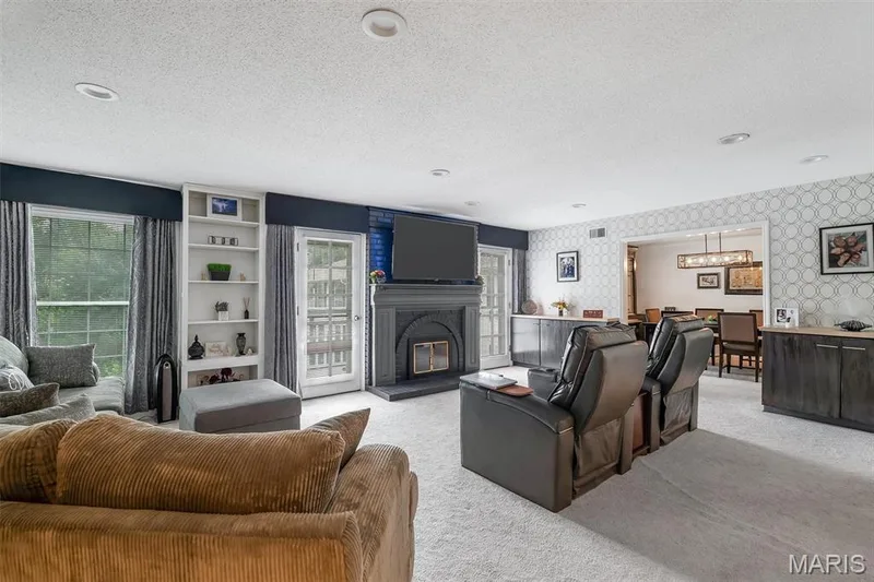 Living room featuring wallpapered walls, light carpet, plenty of natural light, a textured ceiling, and a glass covered fireplace — 1511 Hampton Hall Drive #19 & 20, Chesterfield, MO 63017