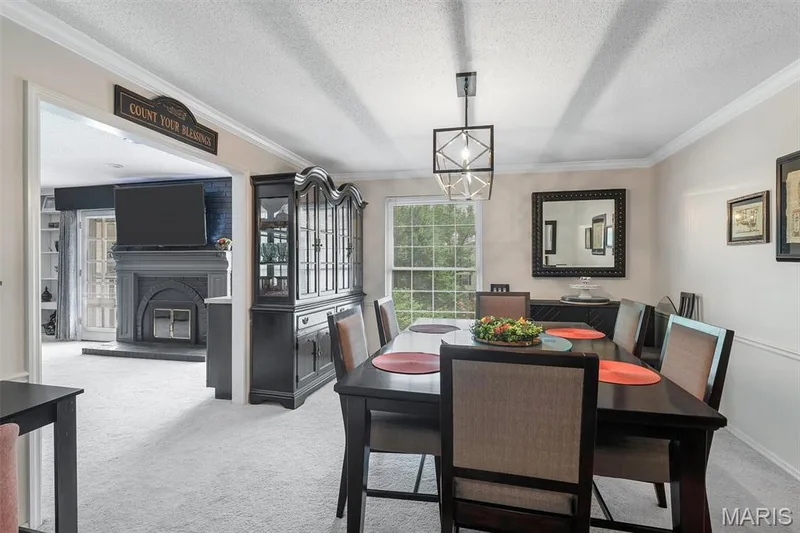 Dining room featuring carpet, ornamental molding, a chandelier, a glass covered fireplace, and a textured ceiling — 1511 Hampton Hall Drive #19 & 20, Chesterfield, MO 63017