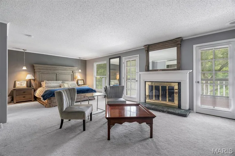 Primary Bedroom featuring access to exterior, carpet flooring, multiple windows, a textured ceiling, and a glass covered fireplace — 1511 Hampton Hall Drive #19 & 20, Chesterfield, MO 63017