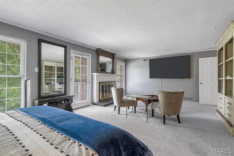 Carpeted bedroom featuring access to outside, multiple windows, a glass covered fireplace, a textured ceiling, and crown molding — 1511 Hampton Hall Drive #19 & 20, Chesterfield, MO 63017
