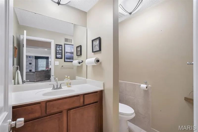 Half bath featuring vanity, a textured ceiling, tile walls, and tile patterned floors — 1511 Hampton Hall Drive #19 & 20, Chesterfield, MO 63017