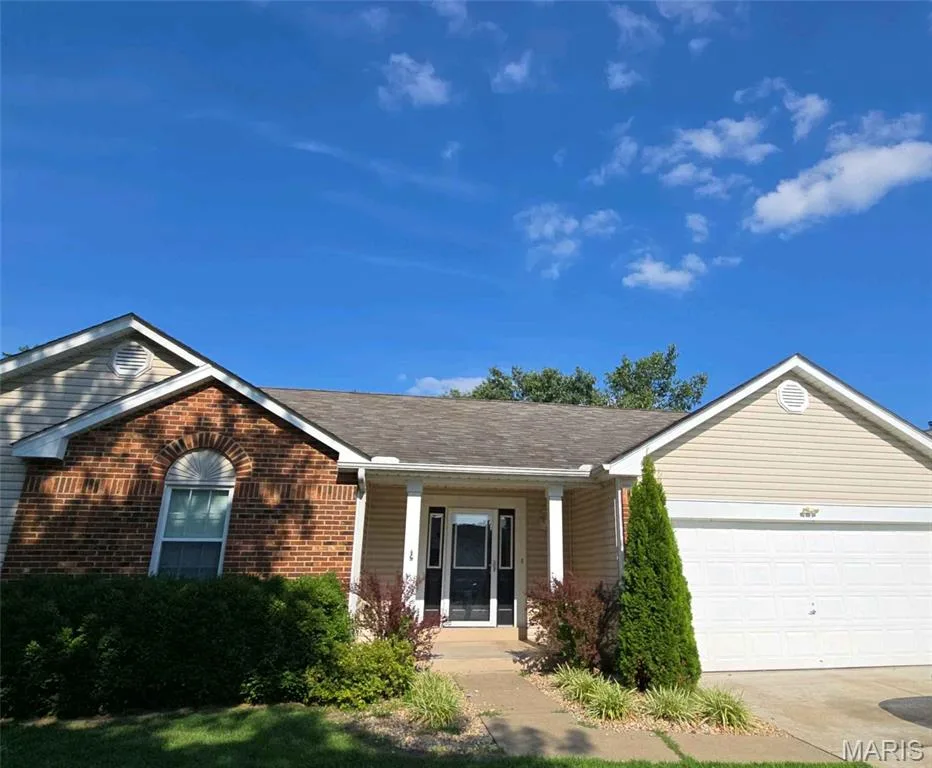 Ranch-style house featuring a garage, driveway, brick siding, a porch, and roof with shingles — 1218 Saddlemaker Drive, St Charles, MO 63304