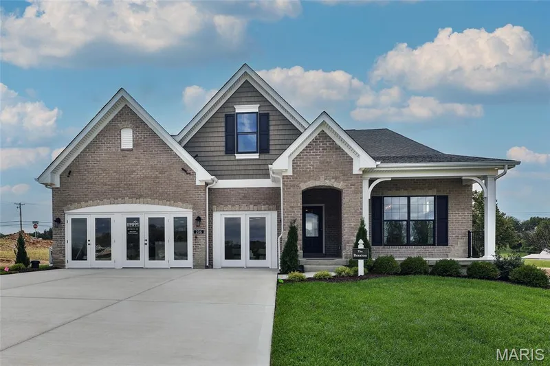 View of front of house with a front yard, brick siding, and covered porch — 0 Braxton @ Montage at Hawk Ridge, Lake St. Louis, MO 63367