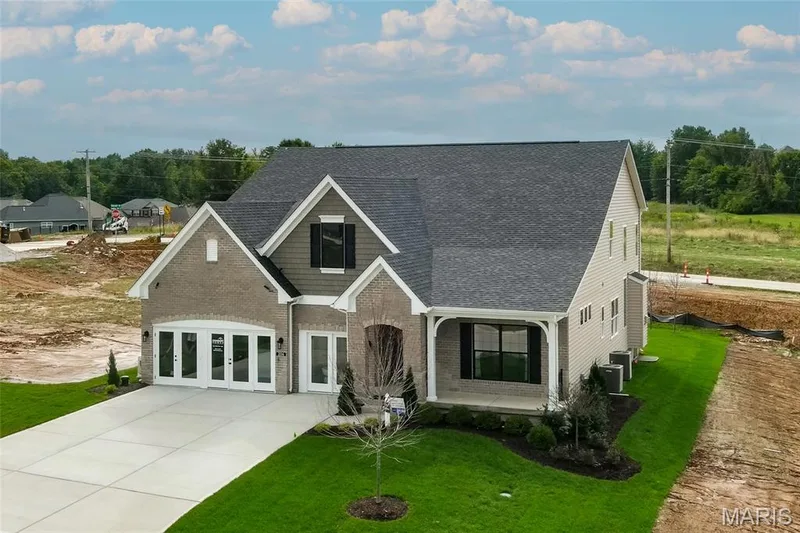 View of front facade featuring a shingled roof, a front yard, brick siding, and concrete driveway — 0 Braxton @ Montage at Hawk Ridge, Lake St. Louis, MO 63367