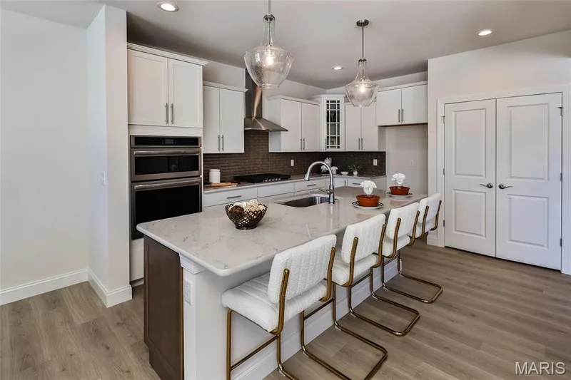 Kitchen with decorative backsplash, light stone countertops, a breakfast bar area, white cabinets, and recessed lighting — 0 Bridgeport - Montage at Hawk Ridge, Lake St. Louis, MO 63367