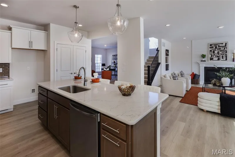 Kitchen featuring a glass covered fireplace, stainless steel dishwasher, recessed lighting, light stone countertops, and a center island with sink — 0 Bridgeport - Montage at Hawk Ridge, Lake St. Louis, MO 63367