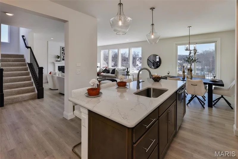 Kitchen featuring dark brown cabinetry, decorative light fixtures, light stone countertops, and light wood-style floors — 0 Bridgeport - Montage at Hawk Ridge, Lake St. Louis, MO 63367