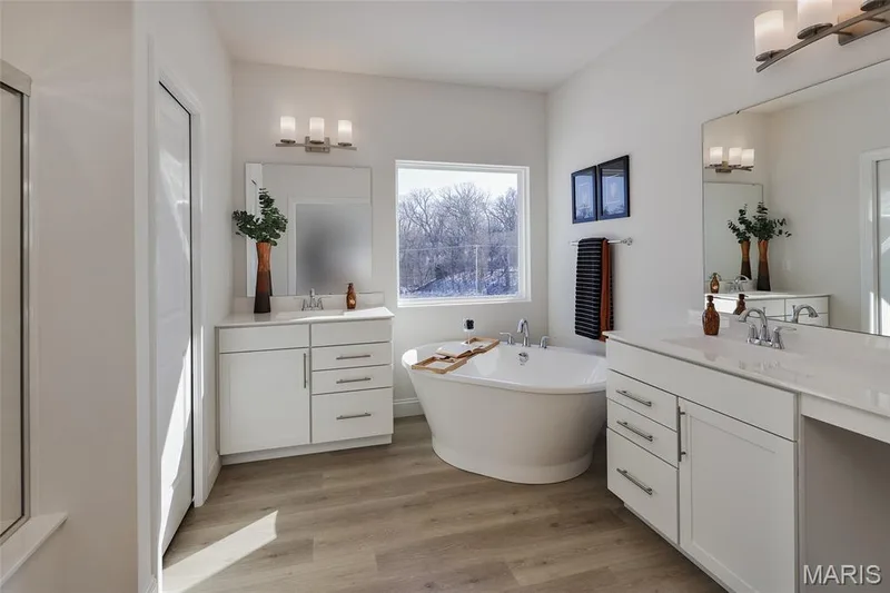 Full bathroom with a freestanding tub, two vanities, and light wood-type flooring — 0 Bridgeport - Montage at Hawk Ridge, Lake St. Louis, MO 63367