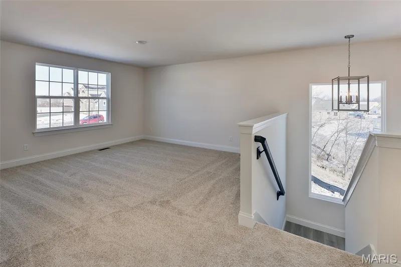 Unfurnished living room featuring light colored carpet and a chandelier — 0 Bridgeport - Montage at Hawk Ridge, Lake St. Louis, MO 63367