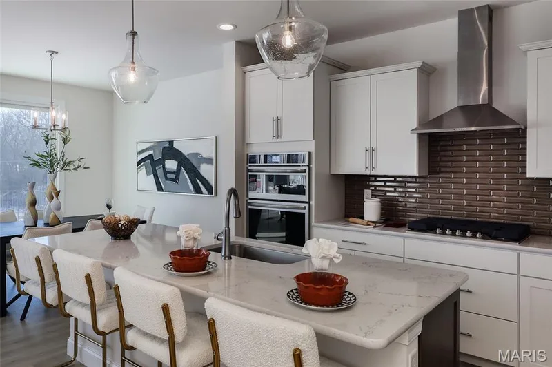 Kitchen with wall chimney exhaust hood, light stone countertops, decorative backsplash, a breakfast bar area, and recessed lighting — 0 Bridgeport - Montage at Hawk Ridge, Lake St. Louis, MO 63367