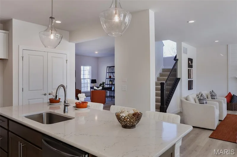 Kitchen with light stone countertops, hanging light fixtures, light wood-style floors, stainless steel dishwasher, and an island with sink — 0 Bridgeport - Montage at Hawk Ridge, Lake St. Louis, MO 63367