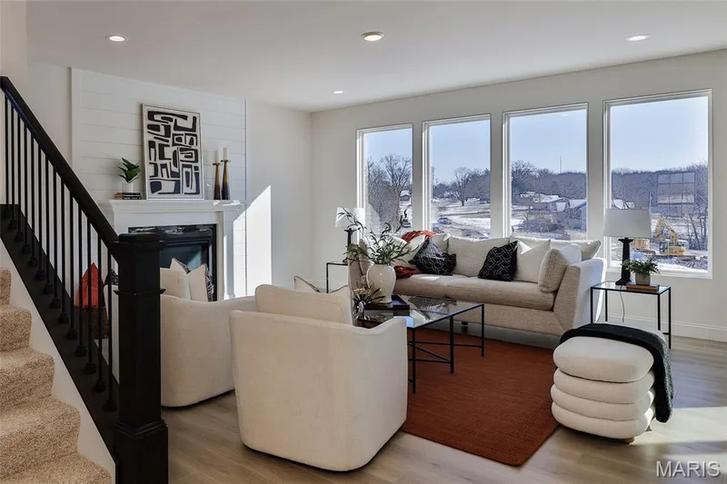 Living room with healthy amount of natural light, a glass covered fireplace, light wood-type flooring, recessed lighting, and stairs — 0 Bridgeport - Montage at Hawk Ridge, Lake St. Louis, MO 63367