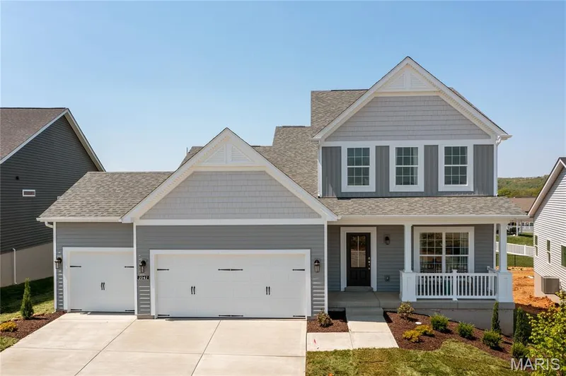 View of front facade with covered porch, roof with shingles, concrete driveway, and an attached garage — 0 Chesapeake @ Montage at Hawk Ridge, Lake St. Louis, MO 63367