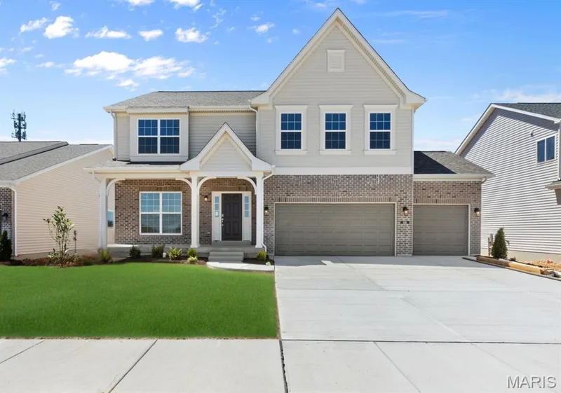 View of front of property with covered porch, driveway, brick siding, a front lawn, and an attached garage — 0 Lancaster @ Montage at Hawk Ridge, Lake St. Louis, MO 63367