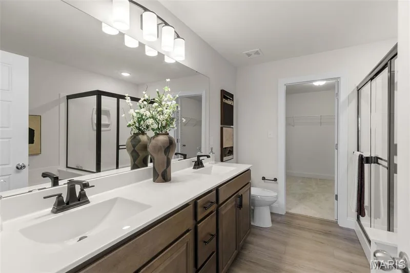 Bathroom featuring a walk in closet, a shower stall, double vanity, and light wood-type flooring — 0 Lancaster @ Montage at Hawk Ridge, Lake St. Louis, MO 63367