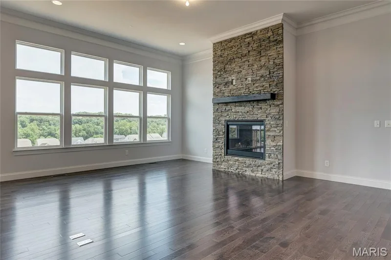 Unfurnished living room featuring crown molding, dark wood-style flooring, and a fireplace — 0 Pierce @ Montage at Hawk Ridge, Lake St. Louis, MO 63367