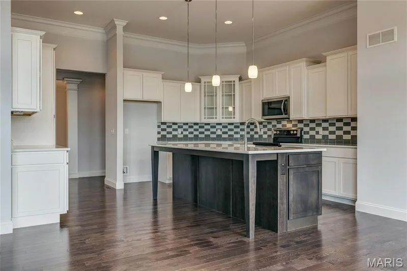 Kitchen with glass insert cabinets, ornamental molding, an island with sink, stainless steel appliances, and a kitchen bar — 0 Pierce @ Montage at Hawk Ridge, Lake St. Louis, MO 63367