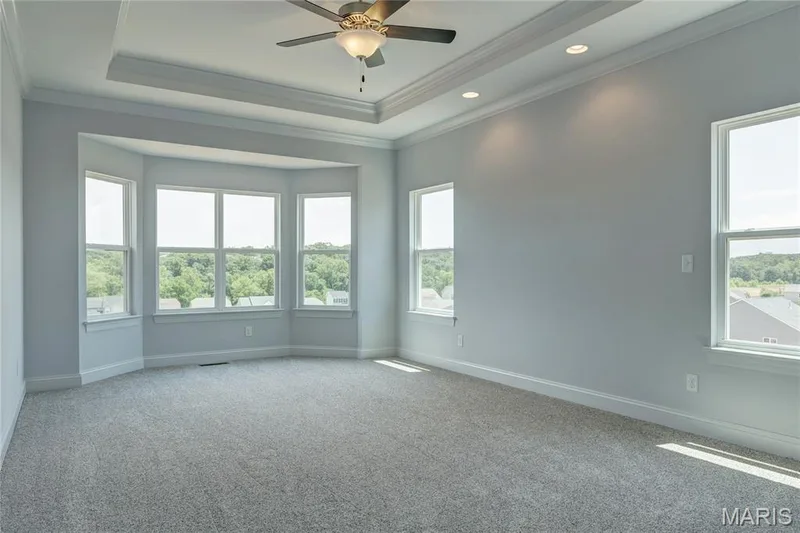 Carpeted empty room featuring a raised ceiling, crown molding, healthy amount of natural light, ceiling fan, and recessed lighting — 0 Pierce @ Montage at Hawk Ridge, Lake St. Louis, MO 63367
