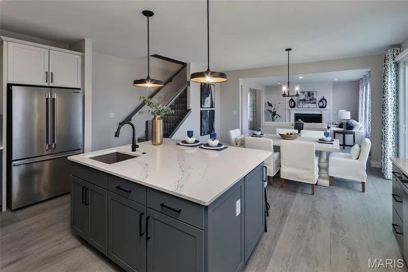 Kitchen with high quality fridge, hanging light fixtures, a center island with sink, a fireplace, and light wood finished floors — 0 Windsor @ Montage at Hawk Ridge, Lake St. Louis, MO 63367