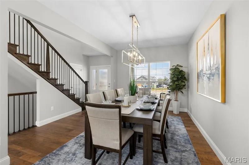 Dining room featuring dark wood finished floors, a chandelier, and stairs — 2 Pin Oak at Hawk Ridge Estate, Lake St. Louis, MO 63367