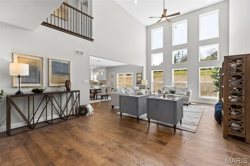 Living area with hardwood / wood-style floors, ceiling fan, a chandelier, and a high ceiling — 2 Pin Oak at Hawk Ridge Estate, Lake St. Louis, MO 63367