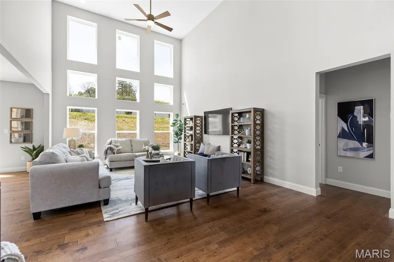 Living area with dark wood-style floors, a ceiling fan, and a high ceiling — 2 Pin Oak at Hawk Ridge Estate, Lake St. Louis, MO 63367