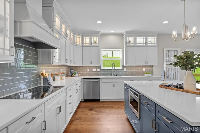 Kitchen with white cabinetry, blue cabinetry, dark wood-style floors, appliances with stainless steel finishes, and recessed lighting — 2 Pin Oak at Hawk Ridge Estate, Lake St. Louis, MO 63367