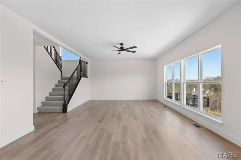 Unfurnished living room with stairway, light wood-type flooring, and ceiling fan — 2 Sequoia at Hawk Ridge Estate, Lake St. Louis, MO 63367