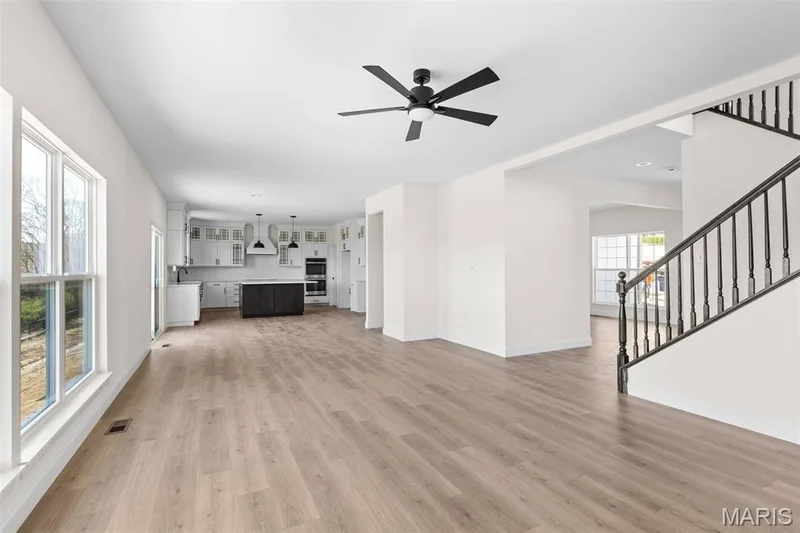 Unfurnished living room with stairway, light wood-style floors, and a ceiling fan — 2 Sequoia at Hawk Ridge Estate, Lake St. Louis, MO 63367