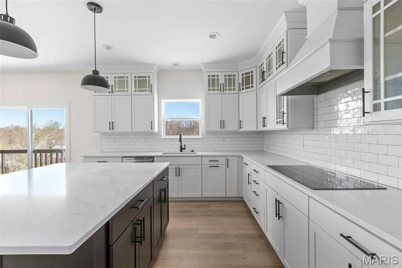 Kitchen featuring tasteful backsplash, hanging light fixtures, white cabinets, custom exhaust hood, and light stone countertops — 2 Sequoia at Hawk Ridge Estate, Lake St. Louis, MO 63367