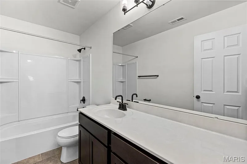 Full bathroom with shower / tub combination, vanity, and dark tile patterned flooring — 563 Edison Way, Wentzville, MO 63385