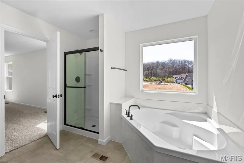 Bathroom with a stall shower, a bath, light tile patterned flooring, and light carpet — 563 Edison Way, Wentzville, MO 63385