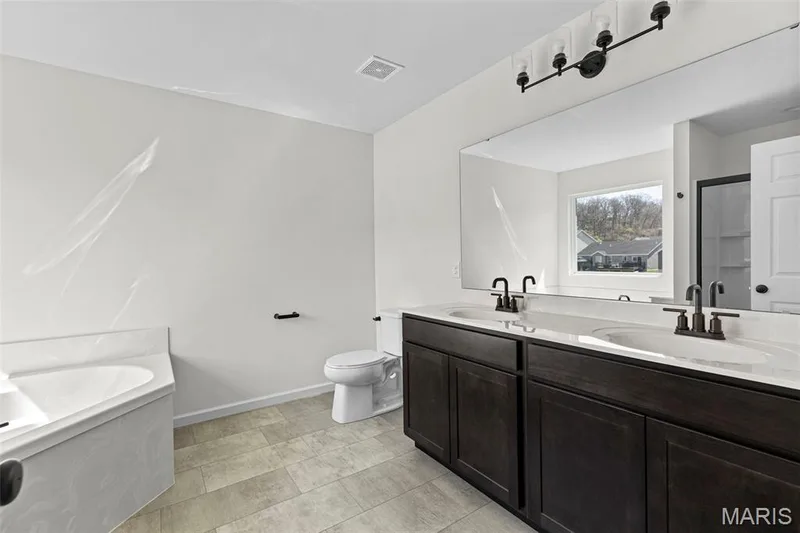 Full bath with a bath, double vanity, a shower stall, and light tile patterned floors — 563 Edison Way, Wentzville, MO 63385