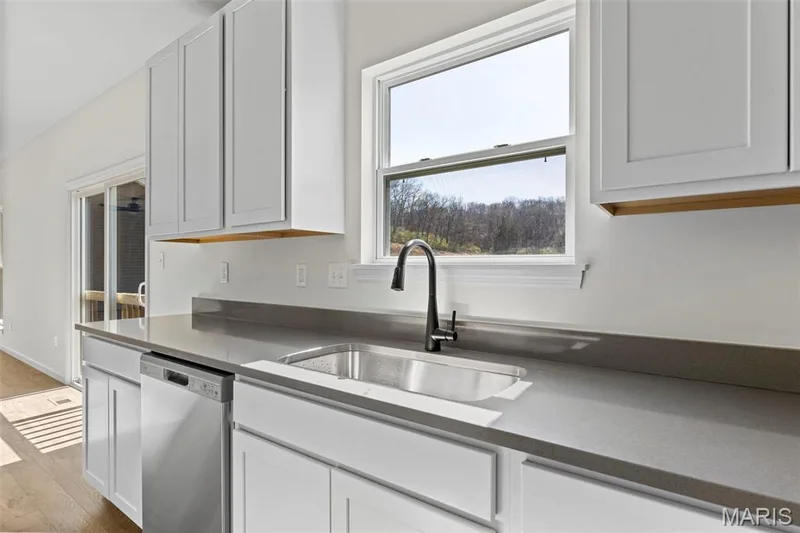 Kitchen featuring stainless steel dishwasher, white cabinets, and light wood finished floors — 563 Edison Way, Wentzville, MO 63385