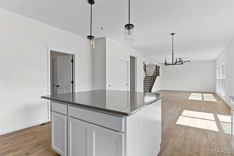 Kitchen featuring light wood-type flooring, dark countertops, decorative light fixtures, a chandelier, and recessed lighting — 563 Edison Way, Wentzville, MO 63385