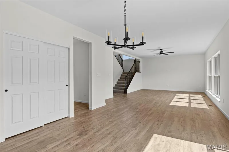 Unfurnished living room with a chandelier, light wood-style flooring, plenty of natural light, and a ceiling fan — 563 Edison Way, Wentzville, MO 63385