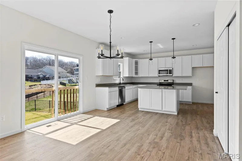Kitchen with a chandelier, light wood-style flooring, stainless steel appliances, decorative light fixtures, and white cabinetry — 563 Edison Way, Wentzville, MO 63385